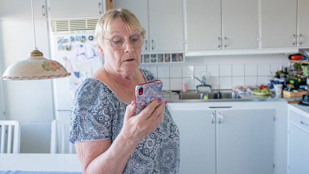En kvinna håller i sin smartphone och tittar på skärmen.