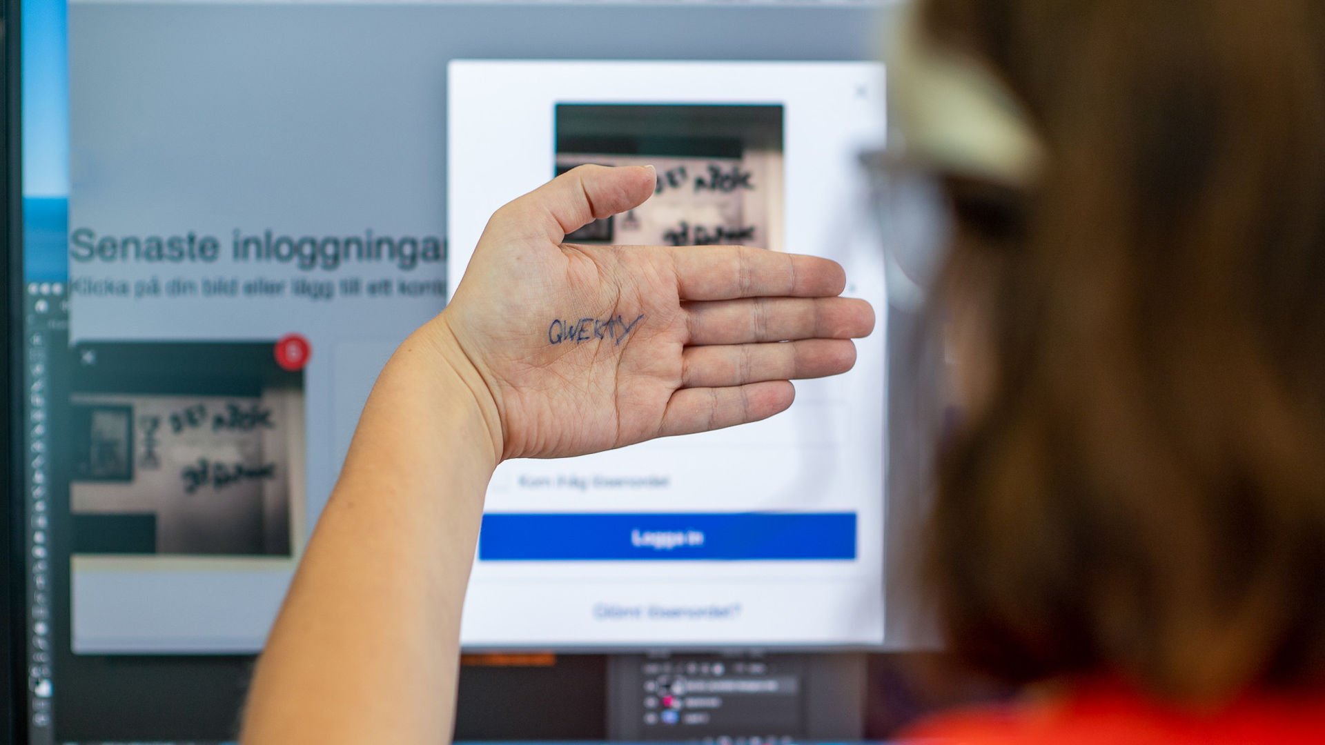 En person sitter framför datorn och håller upp sin hand där lösenordet qwerty syns.