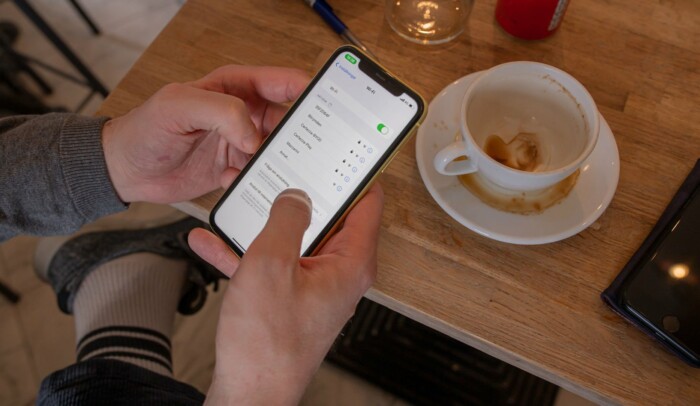 en person håller en mobil i handen, på skärmen syns wifi-inställningar.