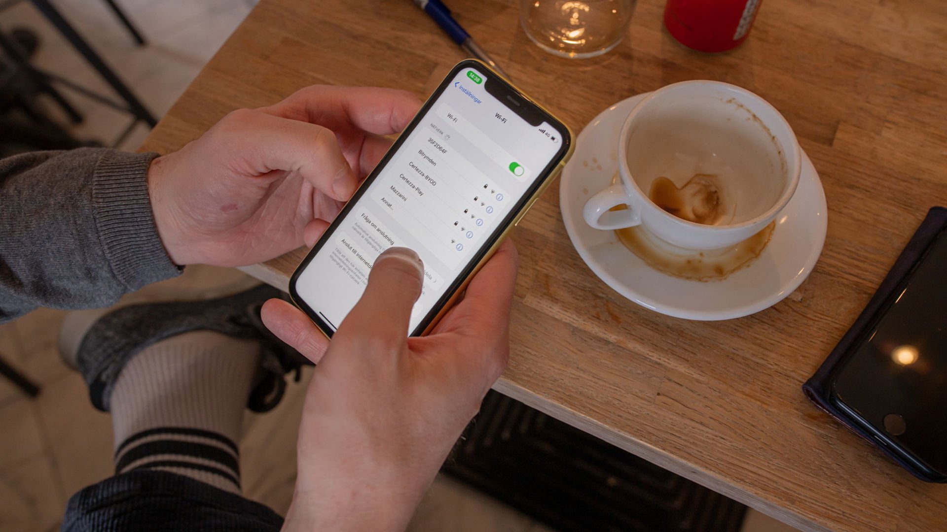 en person håller en mobil i handen, på skärmen syns wifi-inställningar.