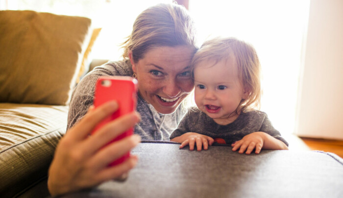 Kvinna och bebis tar en selfie med mobiltelefon.