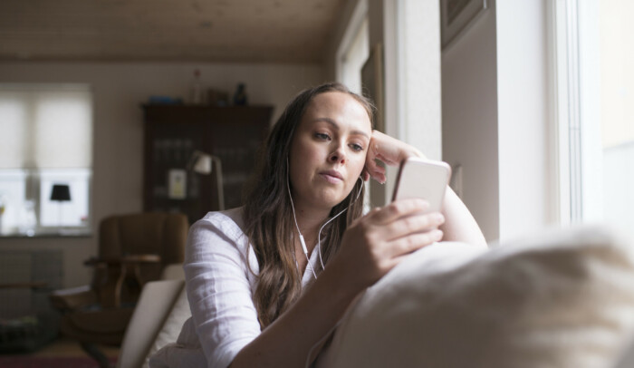 Kvinna som kollar på mobil i soffan. internet www Internetkunskap