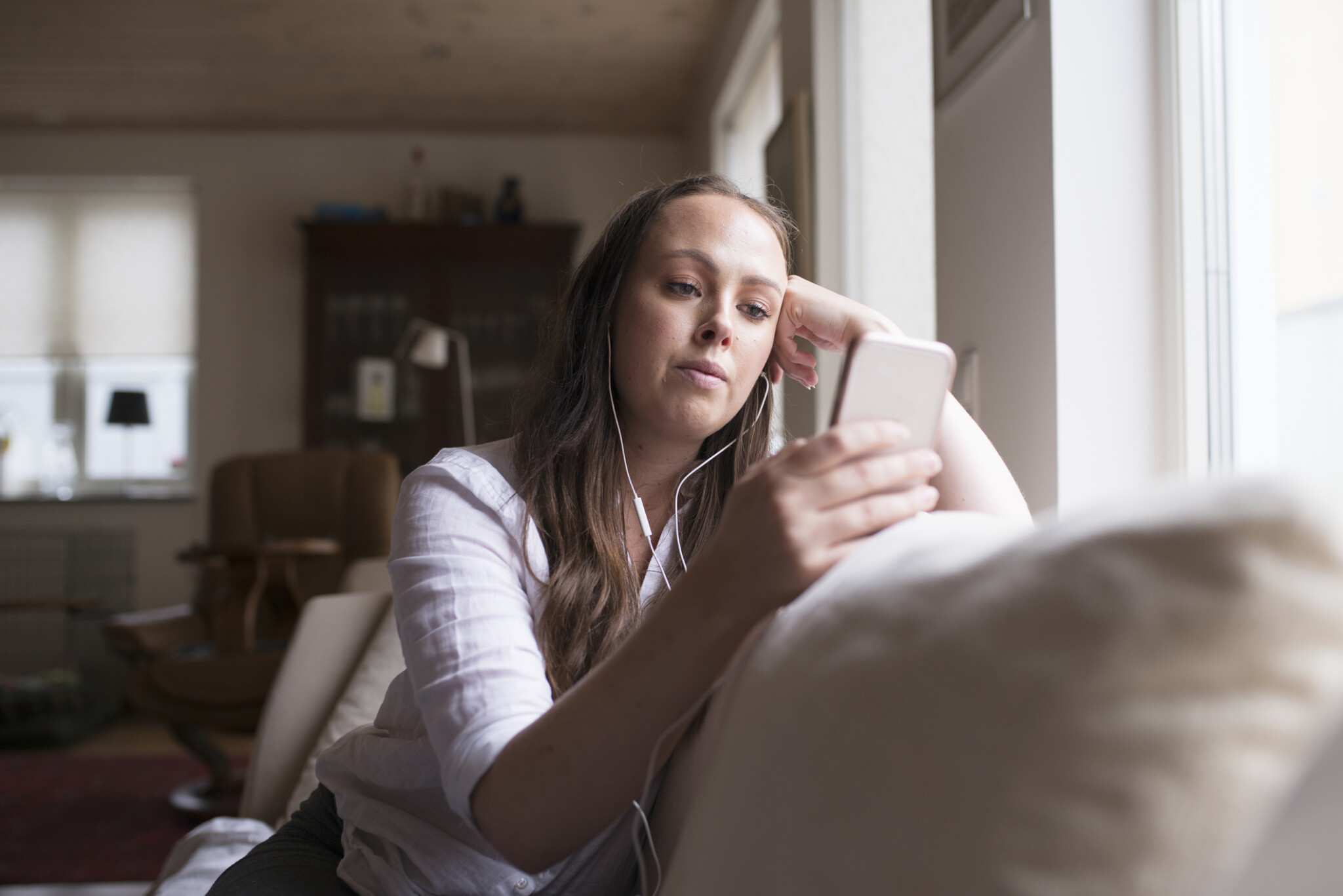 Kvinna som kollar på mobil i soffan. internet www Internetkunskap