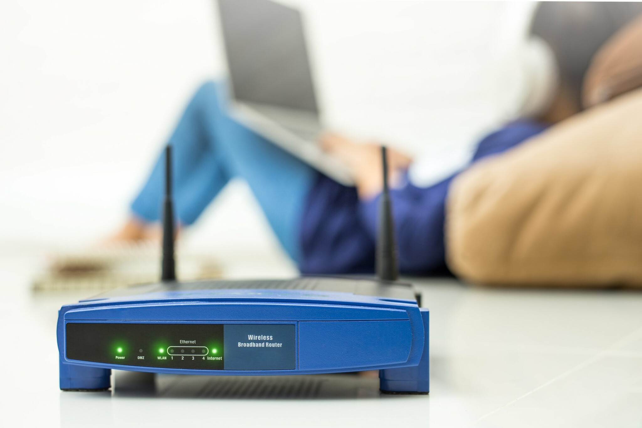 Närbild på router med kvinna som surfar i bakgrunden.