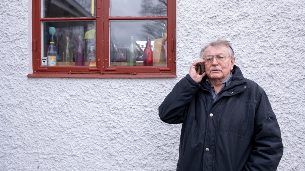 Man står vid ett hus och pratar i telefon