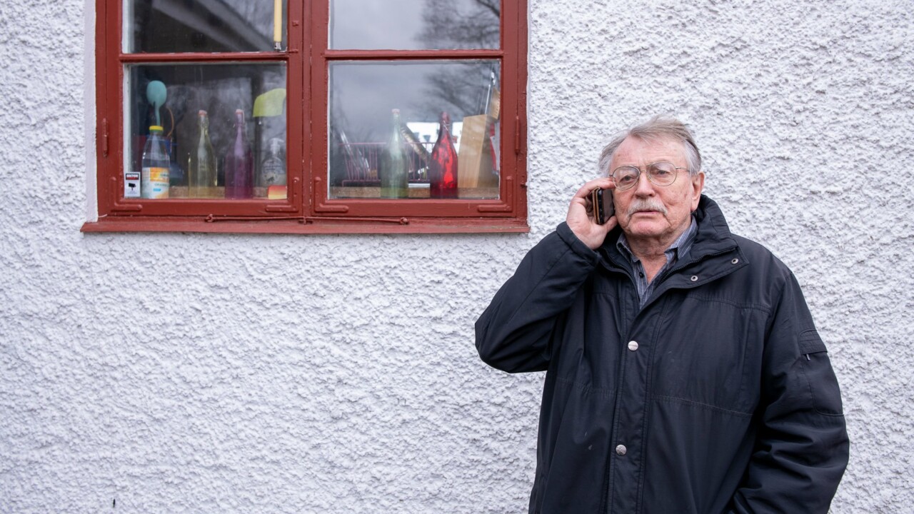 Man står vid ett hus och pratar i telefon
