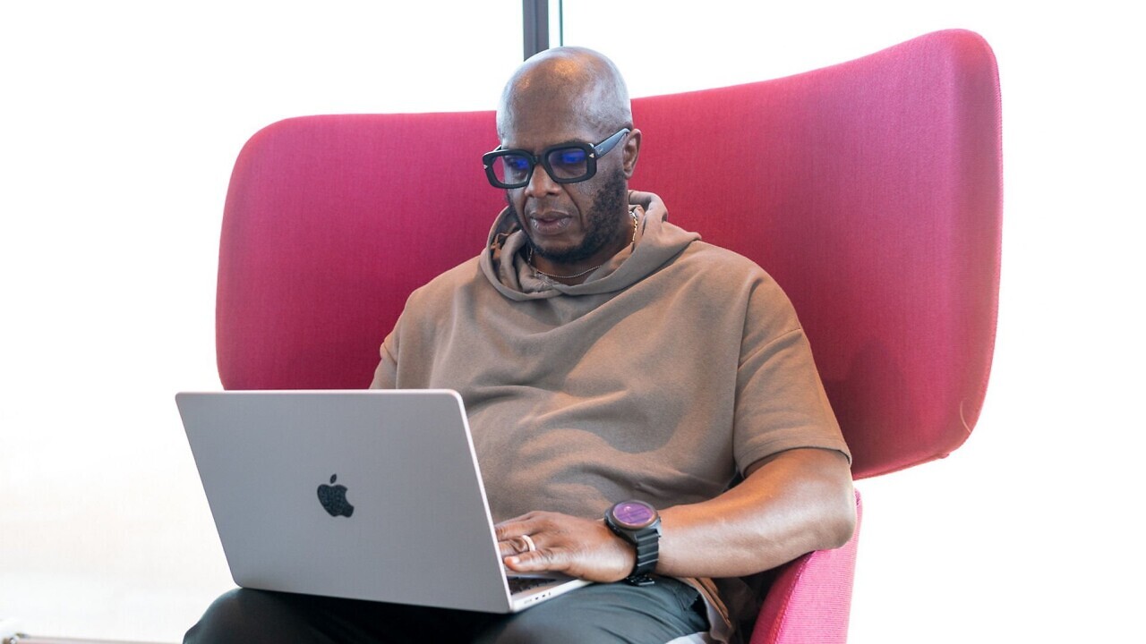 En man sitter i en fåtölj med en laptop i knät