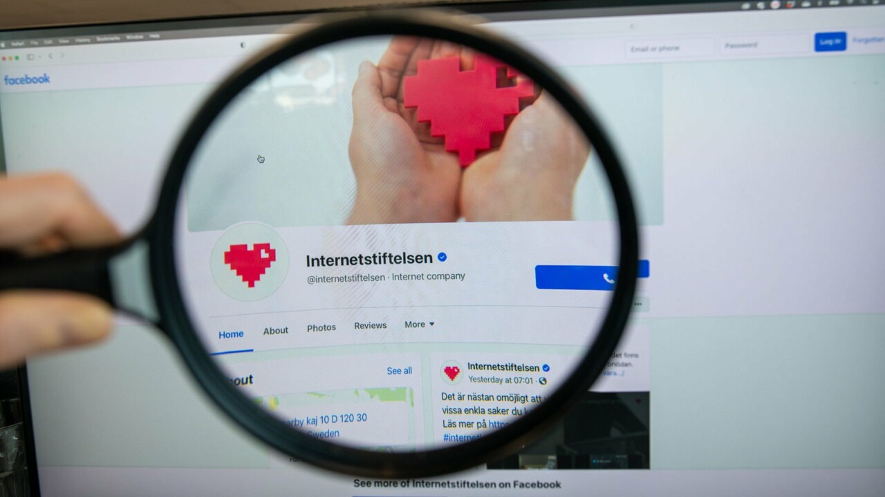 Hand som håller förstoringsglas över en verifierad profil på Facebook.