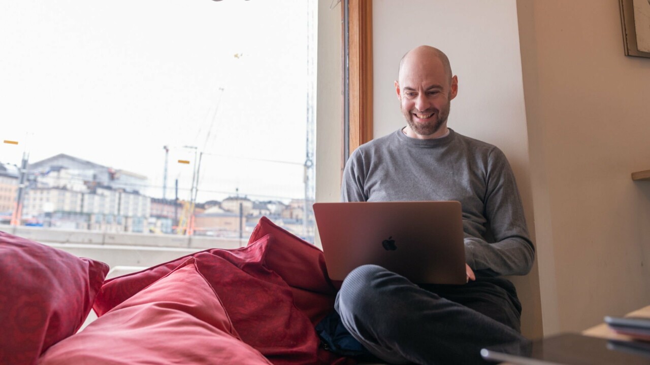 Man sitter med laptop i knät på ett cafe