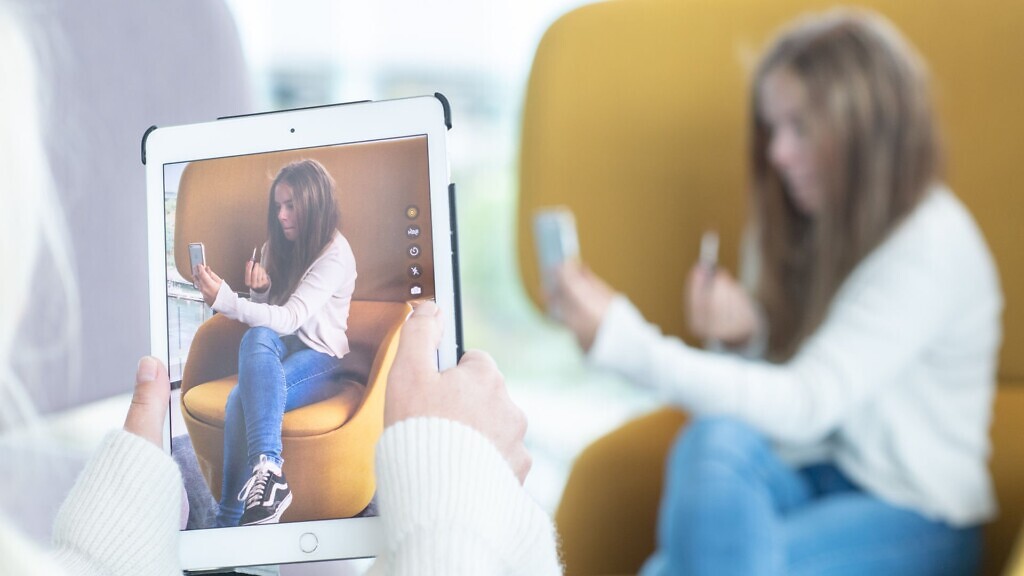 Kvinna fotograferar tonåring som sminkar sig med en iPad.