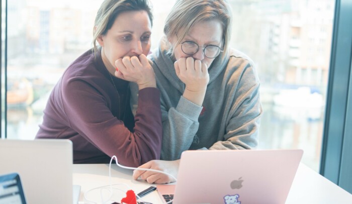 Två personer tittar på datorskärm och funderar vid fönster på Internetstiftelsens kontor.