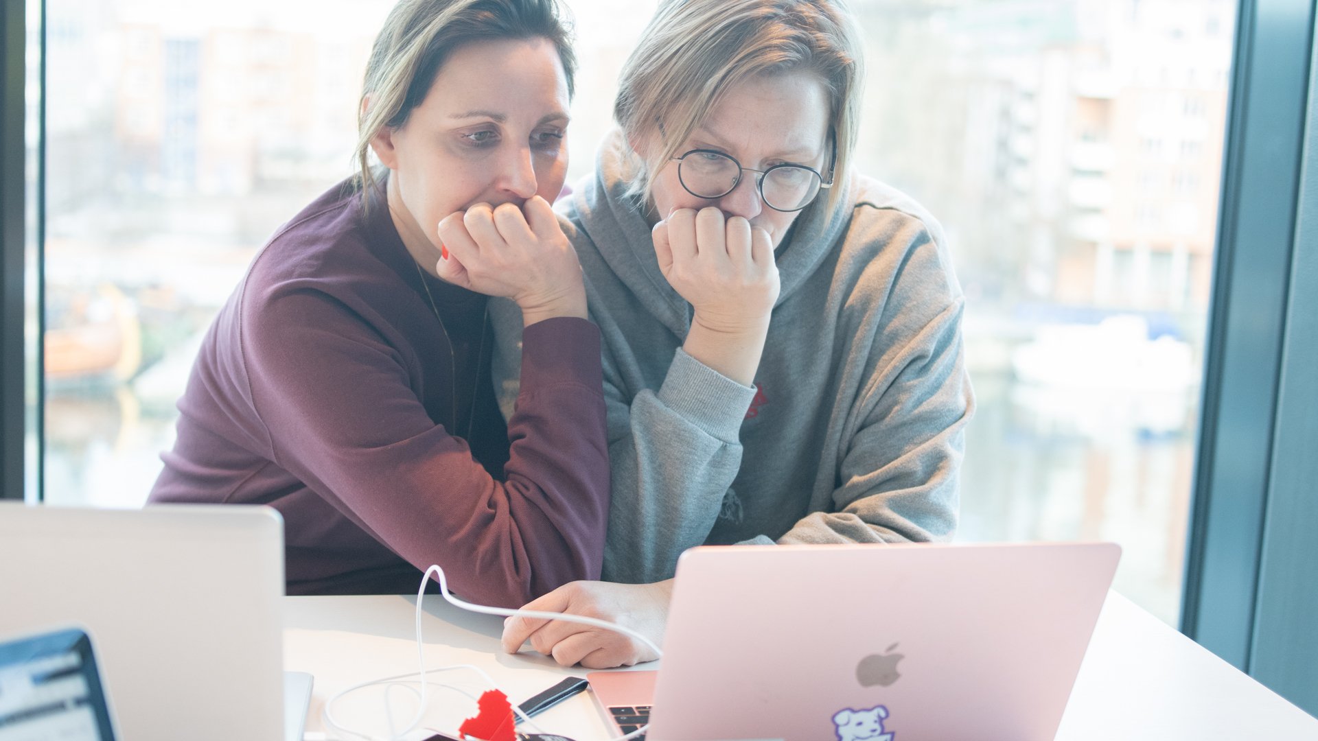 Två personer tittar på datorskärm och funderar vid fönster på Internetstiftelsens kontor.