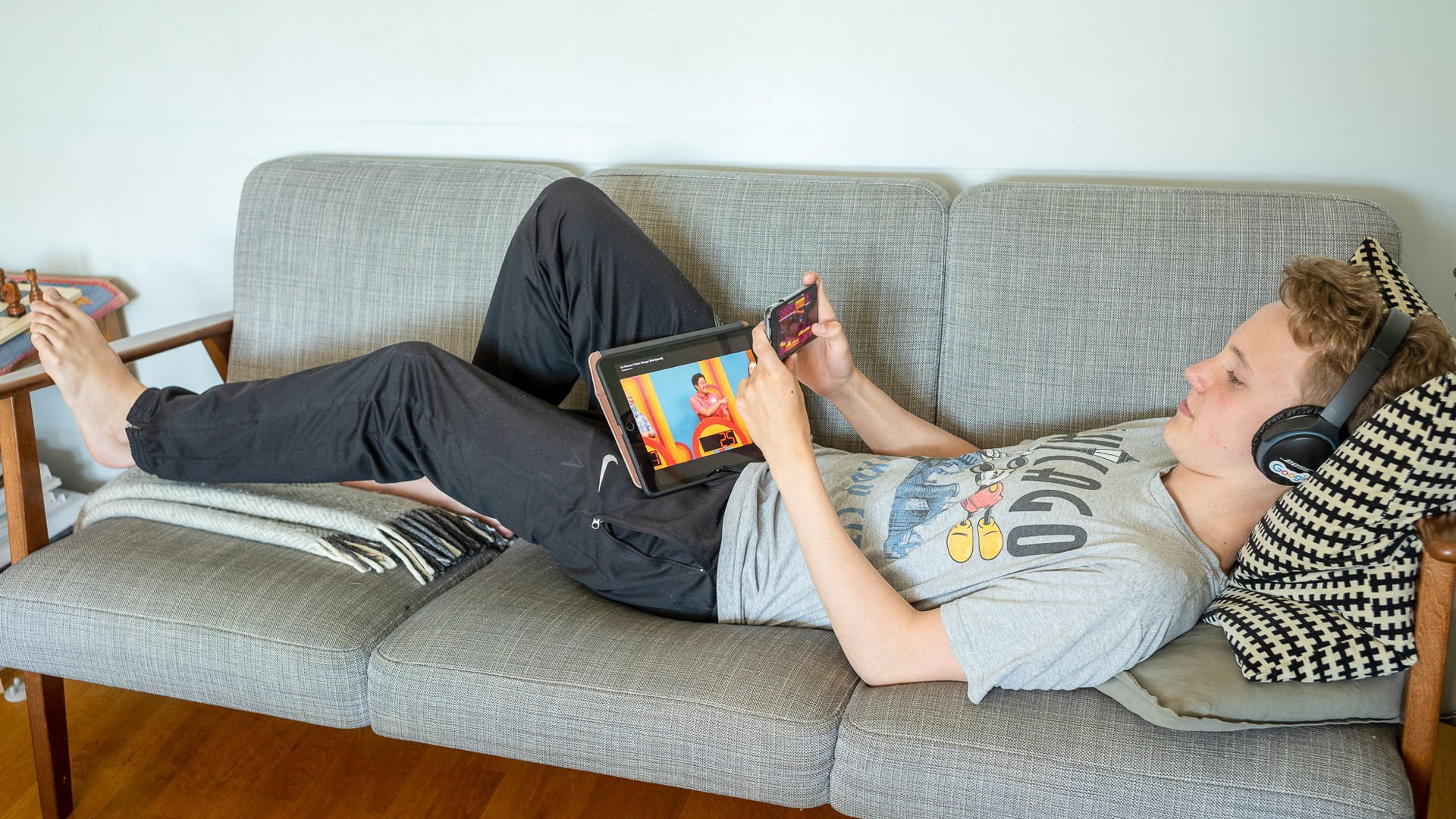 Ett barn ligger i soffan med laptop på magen.