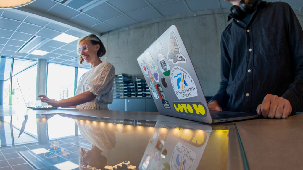 Två personer står vid varsin laptop.