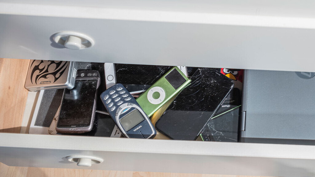 En byrålåda med gamla mobiler, ipods och datorer.