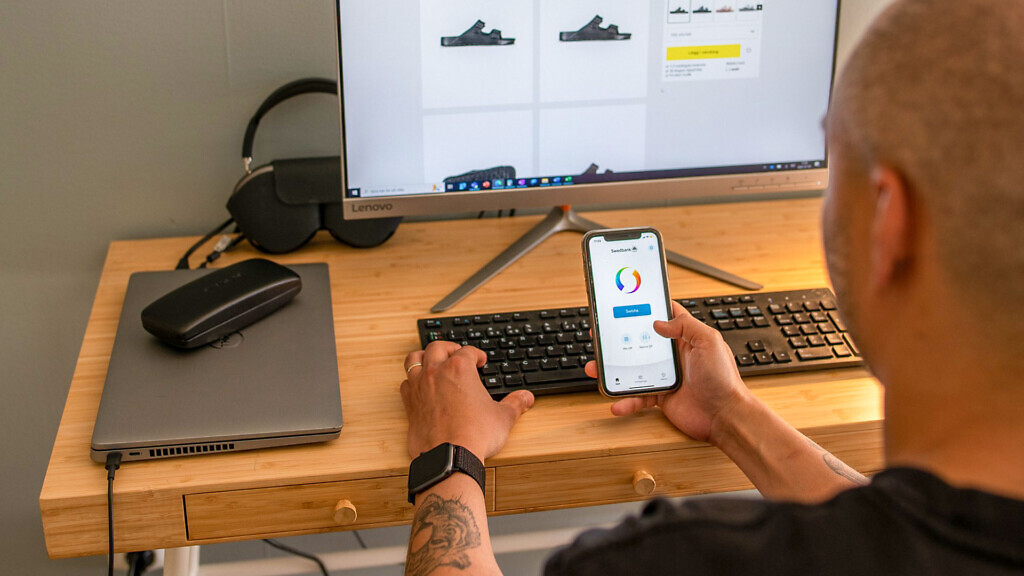 En man sitter vid en dator och betalar med swish i en e-handelsbutik.