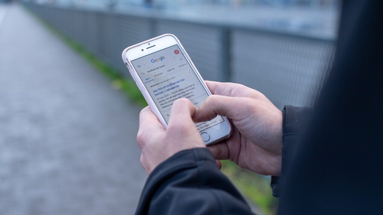 Händer som håller i en mobil, på skärmen syns sökmotorn Google.