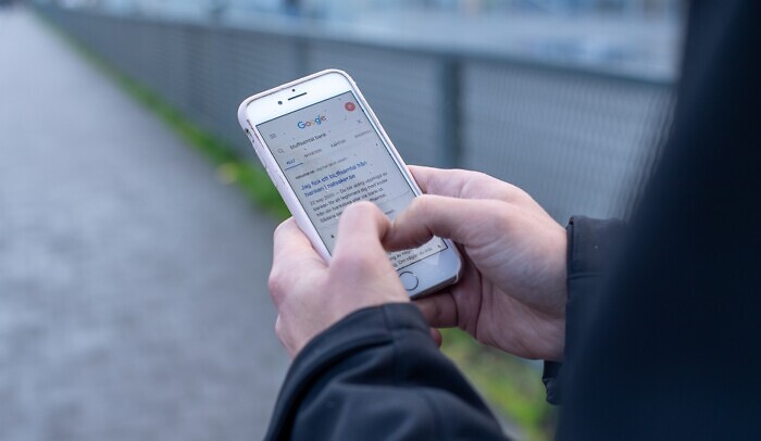 Händer som håller i en mobil, på skärmen syns sökmotorn Google.
