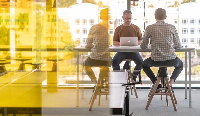 Två personer sitter vid ett högt bord och arbetar på laptops.