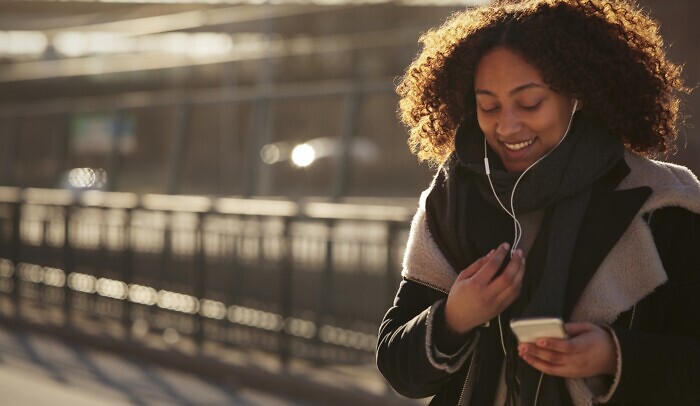 En ung tjej sitter scrollar på sin mobil, det är vinter.