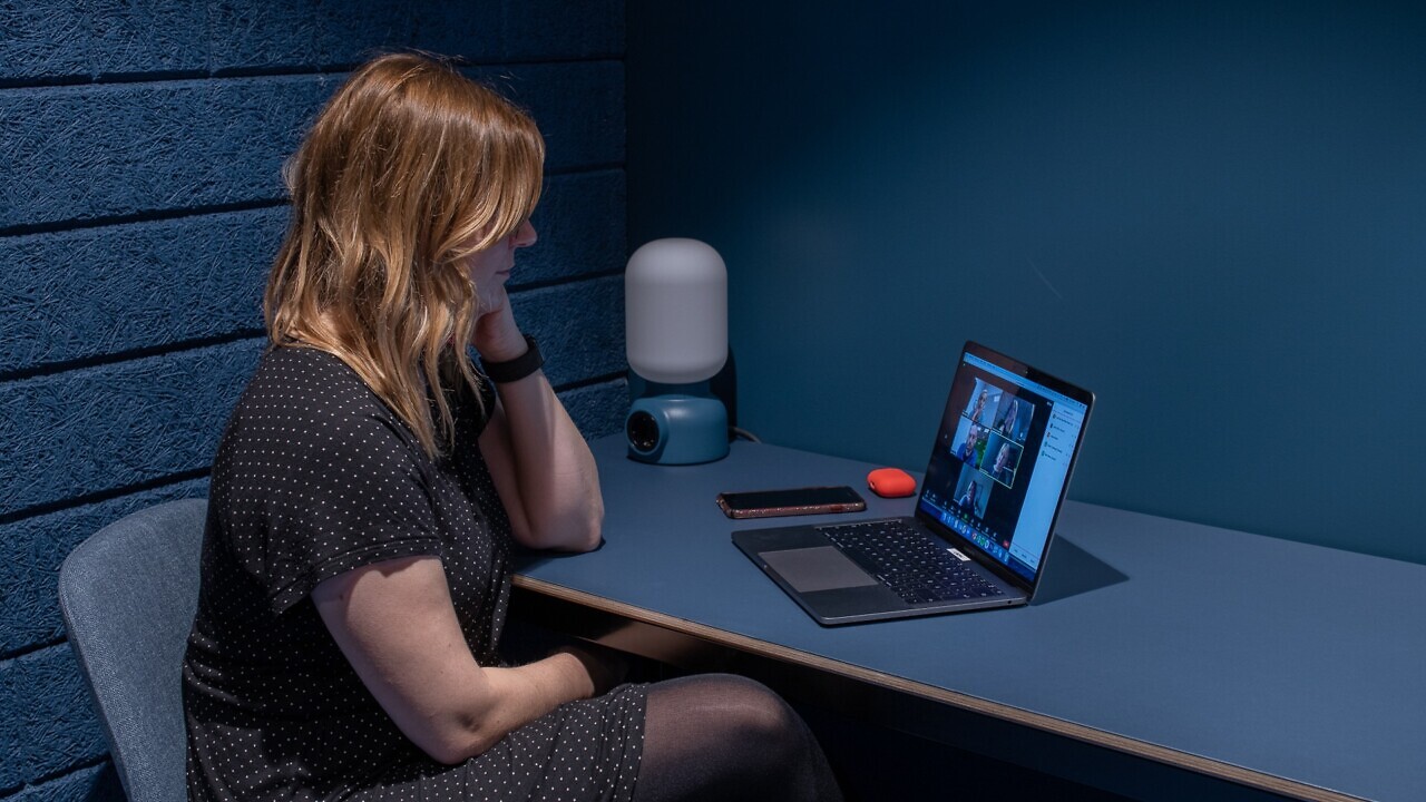 Amanda sitter i ett rum på Goto10 och har datorn och mobiltelefonen på bordet framför sig. På datorskärmen pågår ett digitalt möte.